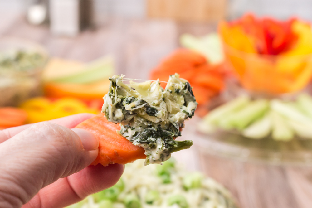 slice of carrot used as a dipper for this spinach artichoke dip